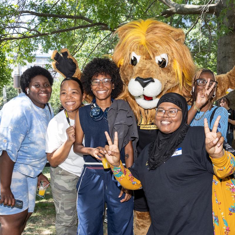 Students standing with Roary smiling at the Camera