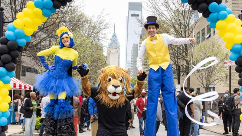 Mascot Roary and stiltwalkers at the block party