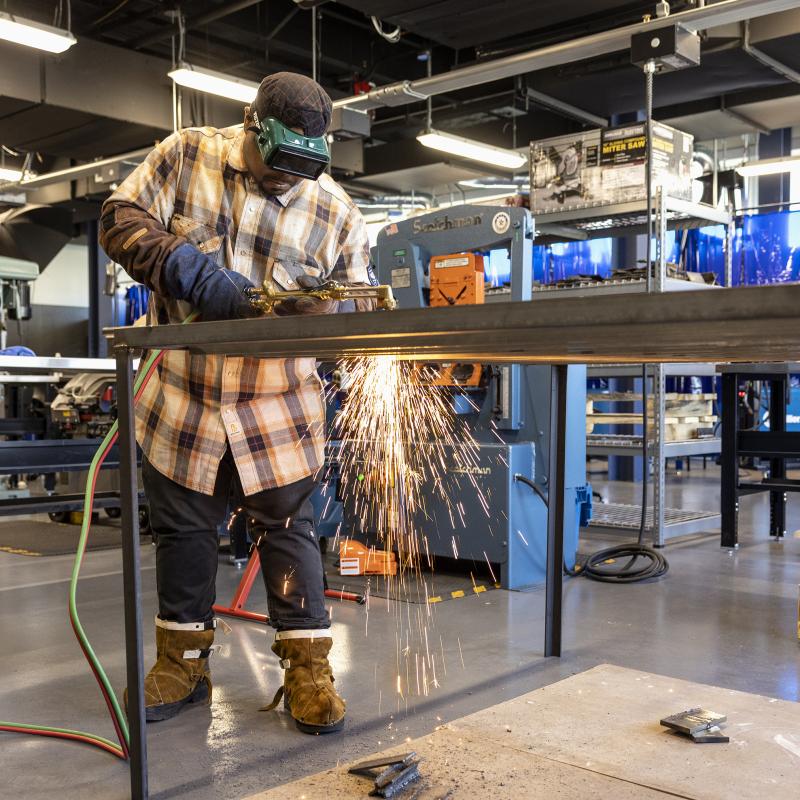 Welding student practices with sparks flying.