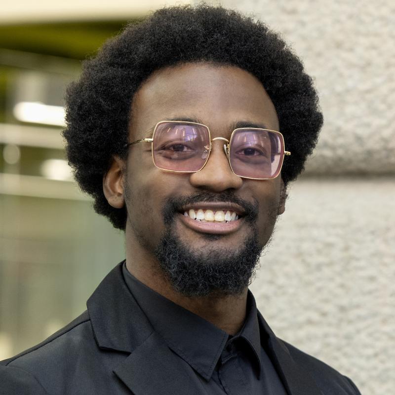 Moo Muhammed smiling, wearing pink sunglasses