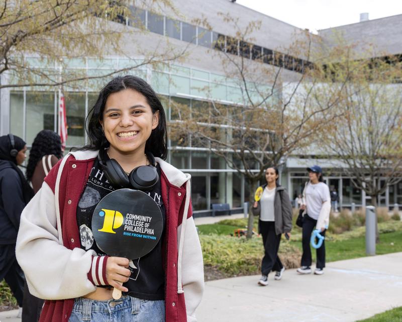 Student in front of the Bonnell Building holding a CCP hand fan