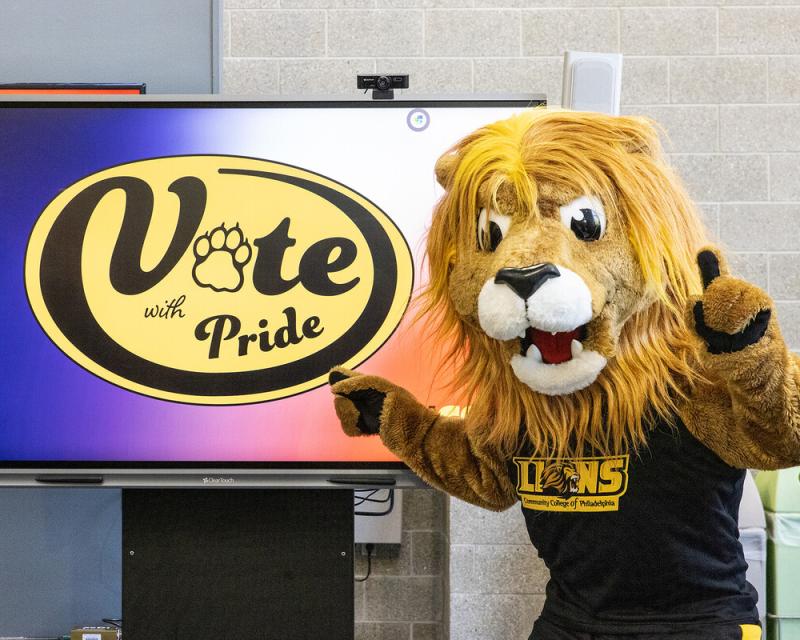 Roary posing in front of a TV that says "Vote with Pride"