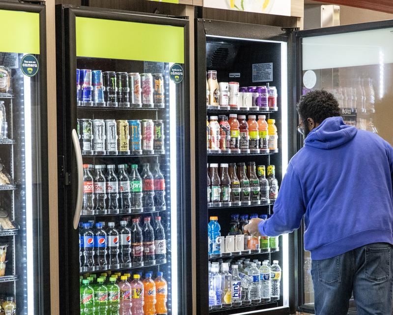 A student opens a cooler and reaches in to pick up a beverage.